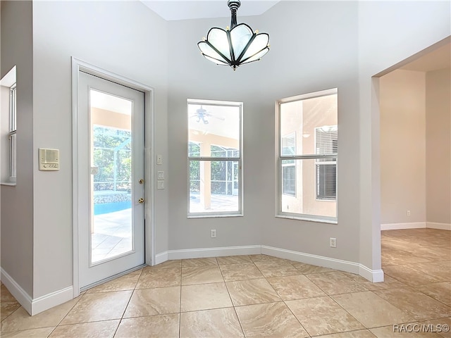 doorway to outside with light tile patterned floors and ceiling fan with notable chandelier