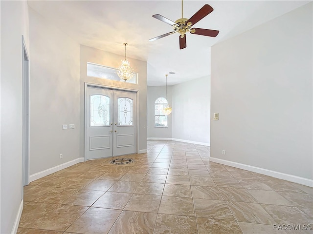 tiled entryway featuring french doors and ceiling fan with notable chandelier