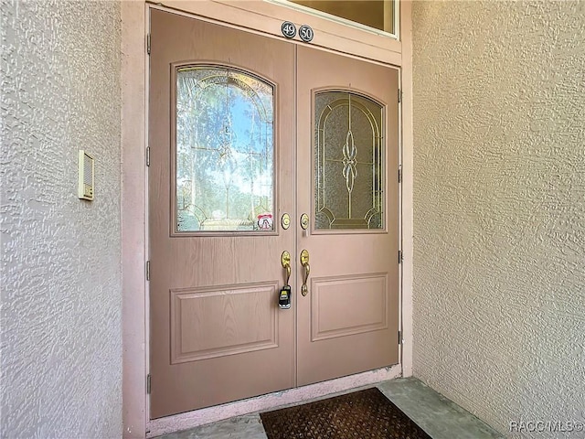 view of exterior entry with stucco siding and french doors