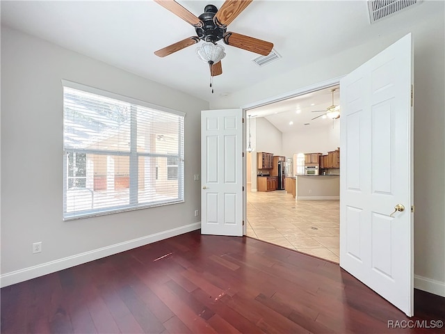 empty room with ceiling fan, lofted ceiling, and light hardwood / wood-style floors