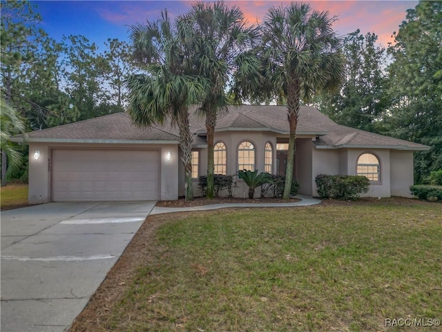 mediterranean / spanish house with a front yard, stucco siding, a garage, and driveway