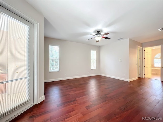 empty room featuring a wealth of natural light, dark hardwood / wood-style flooring, and ceiling fan