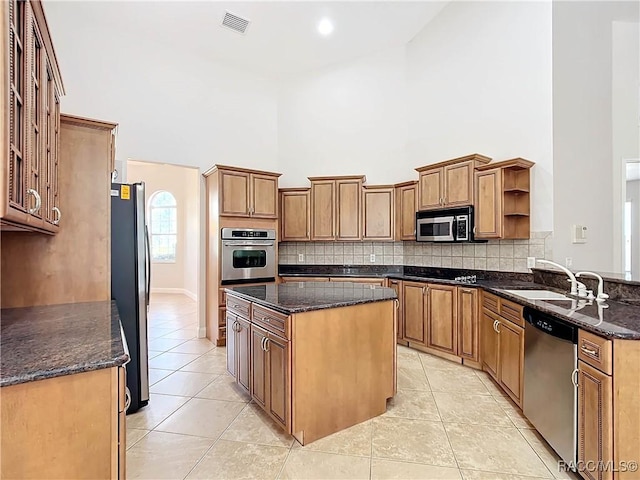 kitchen with stainless steel appliances, tasteful backsplash, a sink, open shelves, and a center island