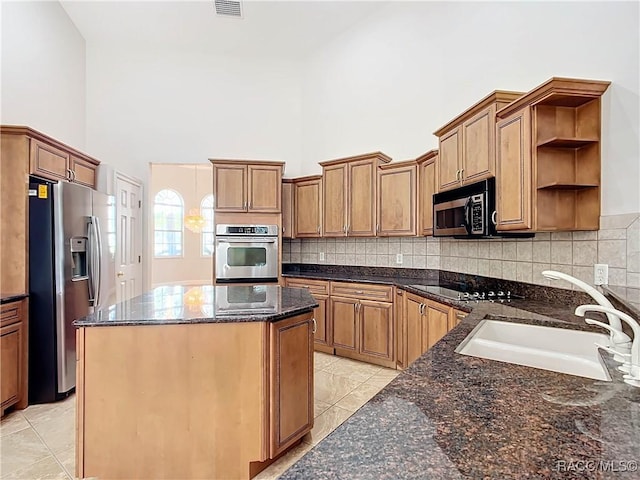 kitchen featuring dark stone countertops, sink, stainless steel appliances, and a high ceiling