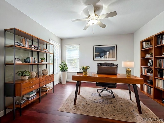 office area with baseboards, ceiling fan, and dark wood-type flooring