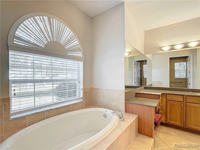 bathroom with a relaxing tiled tub, tile patterned floors, and vanity