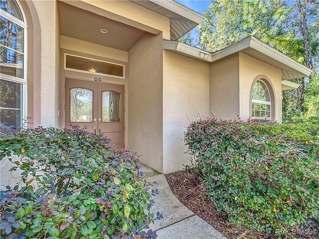 view of exterior entry featuring stucco siding and french doors
