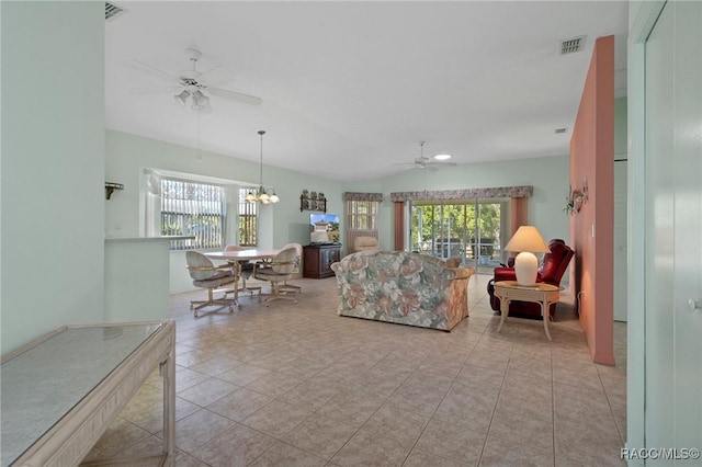 tiled living room with ceiling fan with notable chandelier