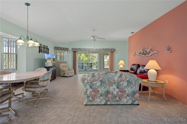 living room with ceiling fan with notable chandelier, vaulted ceiling, and light tile patterned flooring