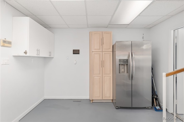 kitchen with a paneled ceiling, concrete floors, and stainless steel refrigerator with ice dispenser