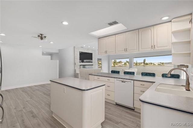 kitchen featuring dishwasher, light hardwood / wood-style floors, a kitchen island, and sink