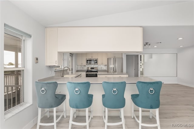 kitchen featuring light hardwood / wood-style flooring, sink, appliances with stainless steel finishes, and vaulted ceiling