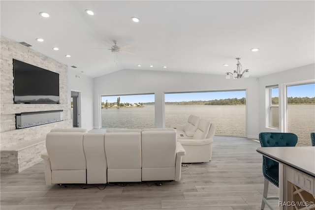 living room featuring a fireplace, light wood-type flooring, ceiling fan with notable chandelier, and vaulted ceiling