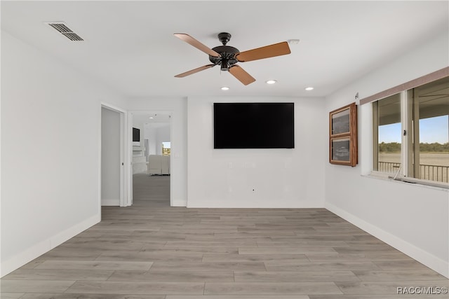 empty room with ceiling fan and light hardwood / wood-style floors