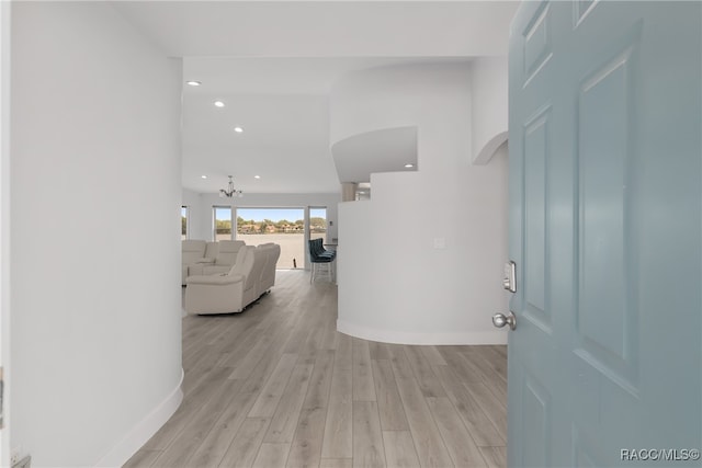 corridor featuring light hardwood / wood-style floors and a notable chandelier