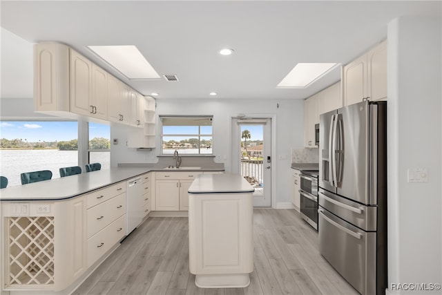 kitchen featuring sink, a kitchen island, stainless steel appliances, and light hardwood / wood-style floors