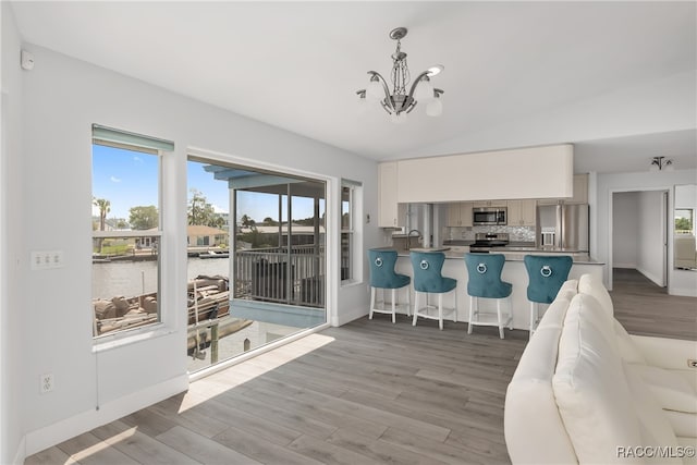 kitchen featuring stainless steel appliances, kitchen peninsula, wood-type flooring, decorative light fixtures, and white cabinets