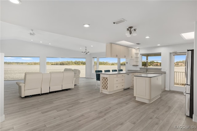 kitchen featuring a center island, light hardwood / wood-style flooring, stainless steel fridge, lofted ceiling, and ceiling fan with notable chandelier