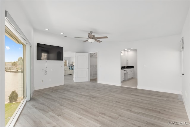 unfurnished living room featuring light wood-type flooring and ceiling fan