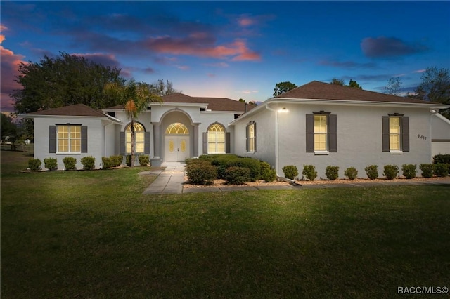 mediterranean / spanish house featuring a front lawn, french doors, and stucco siding