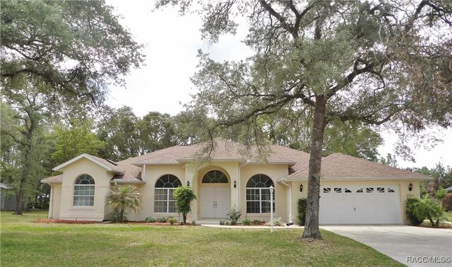 view of front of house with stucco siding, an attached garage, driveway, and a front lawn