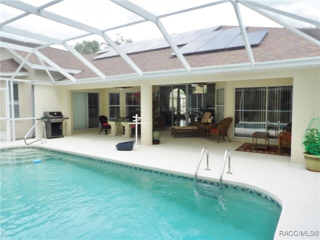 outdoor pool with grilling area, a lanai, and a patio area