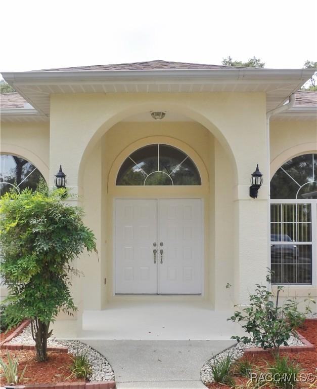 doorway to property featuring a shingled roof and stucco siding