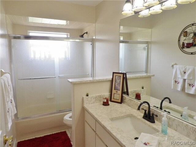 bathroom featuring vanity, shower / bath combination with glass door, and toilet