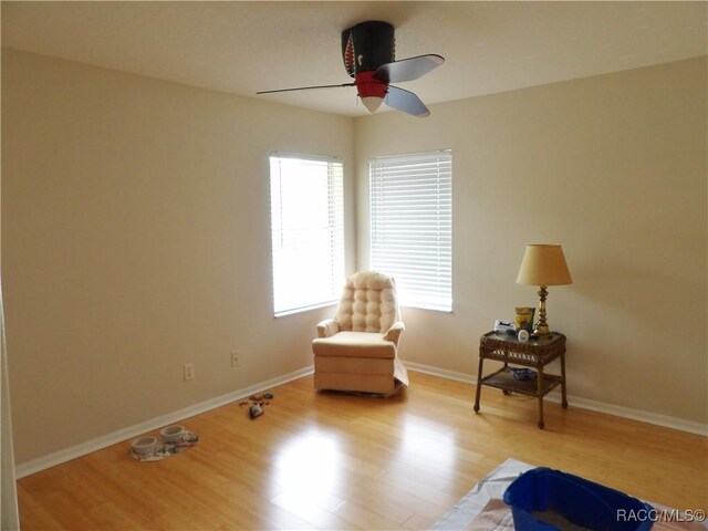 sitting room featuring baseboards, wood finished floors, and ceiling fan