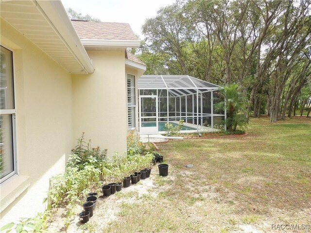 view of yard with an outdoor pool and glass enclosure