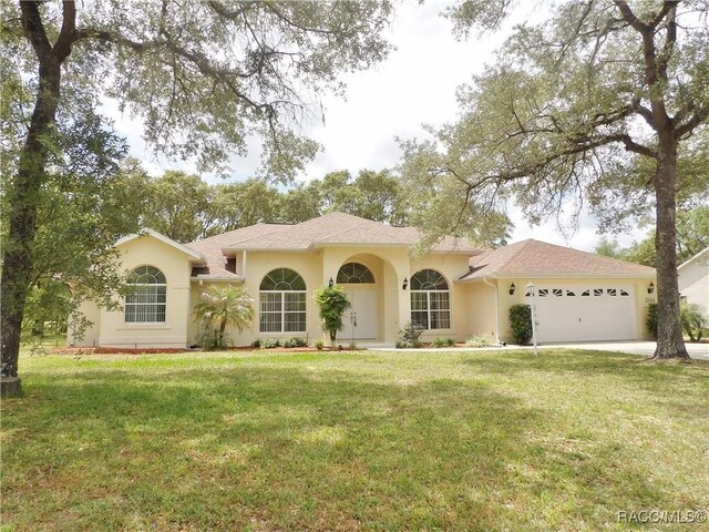 view of front of house with stucco siding, driveway, a front yard, and a garage