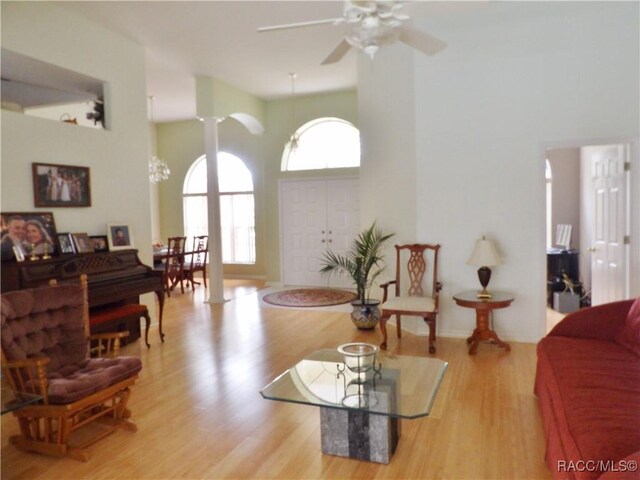 living area with wood finished floors and ceiling fan with notable chandelier