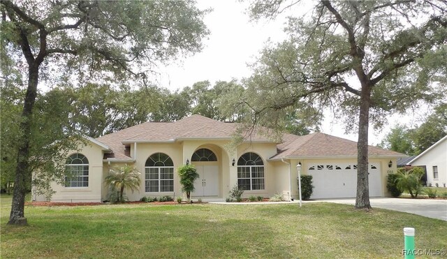view of front of house featuring a garage, concrete driveway, a front yard, stucco siding, and roof with shingles