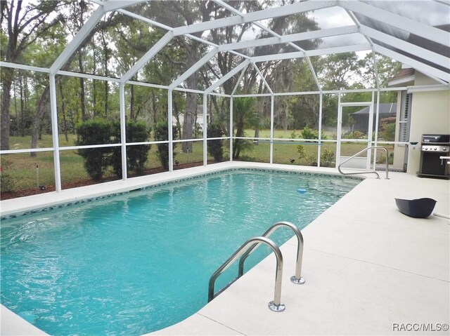 outdoor pool with grilling area, a patio area, and a lanai