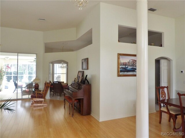 interior space with wood finished floors, arched walkways, a notable chandelier, visible vents, and ornate columns