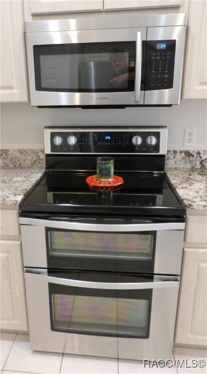 details featuring light stone countertops, white cabinetry, and appliances with stainless steel finishes