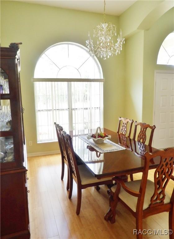 dining area featuring light wood finished floors, baseboards, and a notable chandelier
