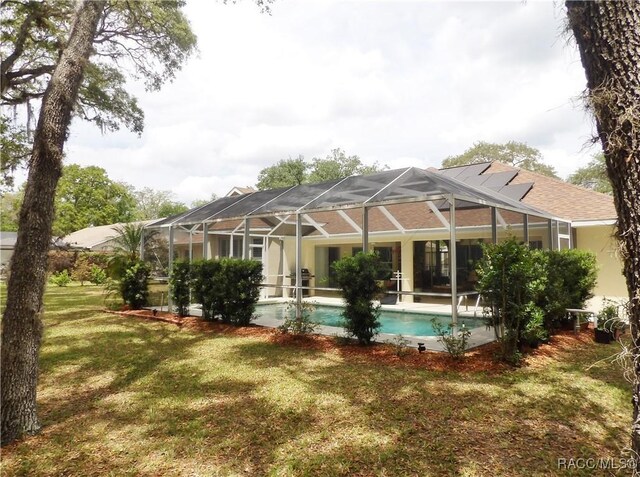 back of property featuring an outdoor pool, a yard, and stucco siding