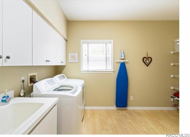 clothes washing area with cabinets, separate washer and dryer, sink, and light hardwood / wood-style floors