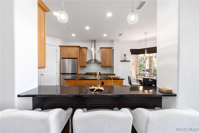 1147 W Pointe Vista Path Unit C1, Hernando, FL 34442 - kitchen featuring freestanding refrigerator, wall chimney range hood, dark countertops, backsplash, and a peninsula