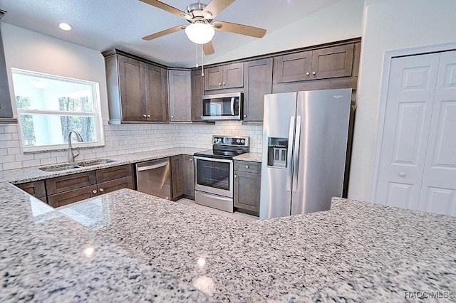 kitchen with light stone counters, appliances with stainless steel finishes, sink, and tasteful backsplash