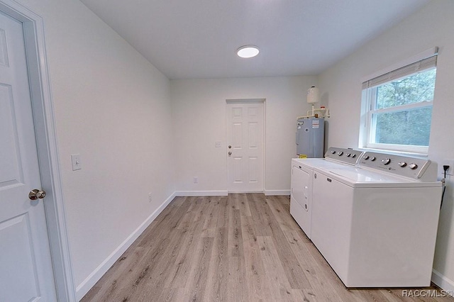 laundry area with electric water heater, washing machine and clothes dryer, and light hardwood / wood-style flooring