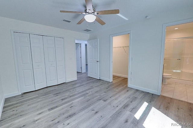 unfurnished bedroom featuring ensuite bath, light hardwood / wood-style floors, a closet, and ceiling fan