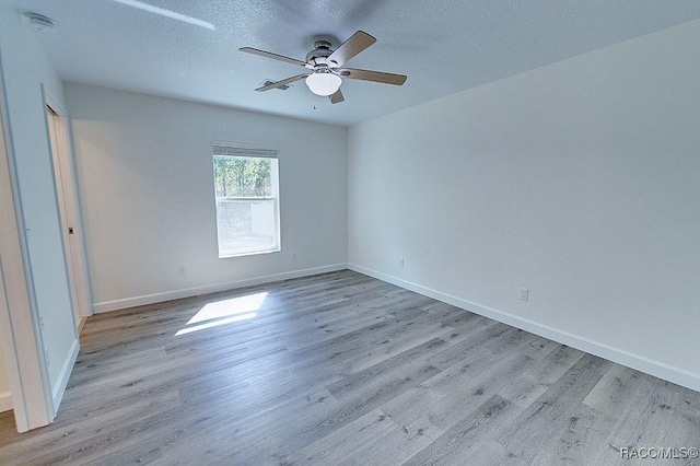 spare room with ceiling fan, light hardwood / wood-style floors, and a textured ceiling