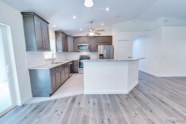 kitchen with sink, a center island, light hardwood / wood-style flooring, stainless steel appliances, and decorative backsplash