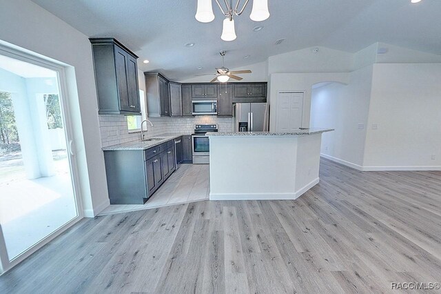 kitchen with sink, tasteful backsplash, decorative light fixtures, a center island, and appliances with stainless steel finishes