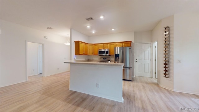 1553 E Pacific Ln, Inverness, FL 34453 - kitchen with stainless steel appliances, light wood finished floors, brown cabinetry, light countertops, and a peninsula