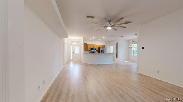 1553 E Pacific Ln, Inverness, FL 34453 - unfurnished living room with a ceiling fan, a chandelier, light wood-type flooring, and baseboards