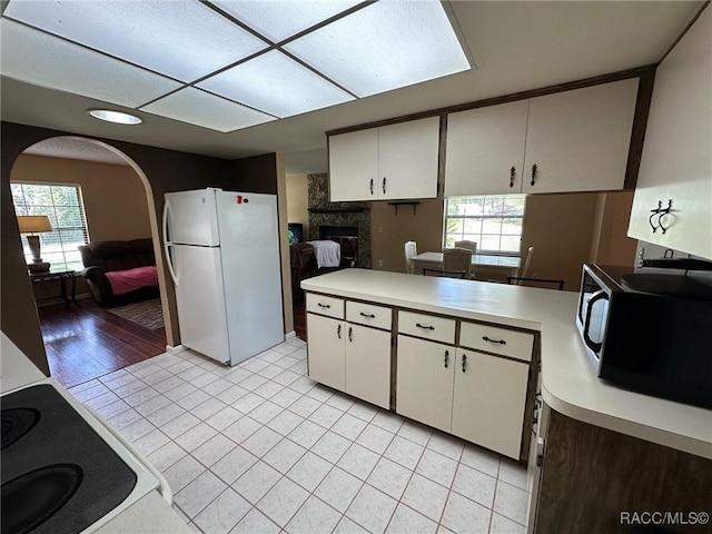 2510 W Dolphin Dr, Citrus Springs, FL 34434 - kitchen featuring freestanding refrigerator, black microwave, light countertops, arched walkways, and healthy amount of natural light
