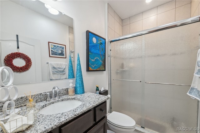 bathroom with vanity, toilet, and a shower with door